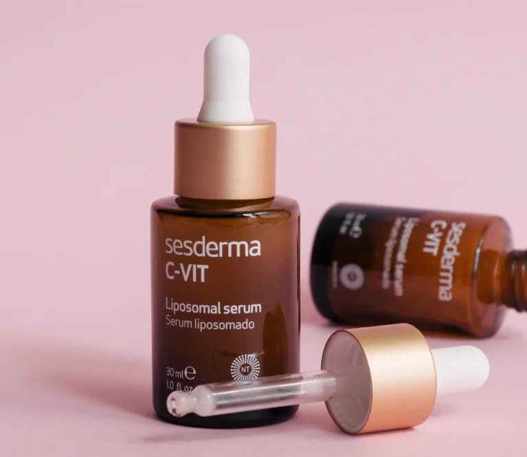 Sesderma C-VIT liposomal serum bottles with dropper, displayed on a pink background