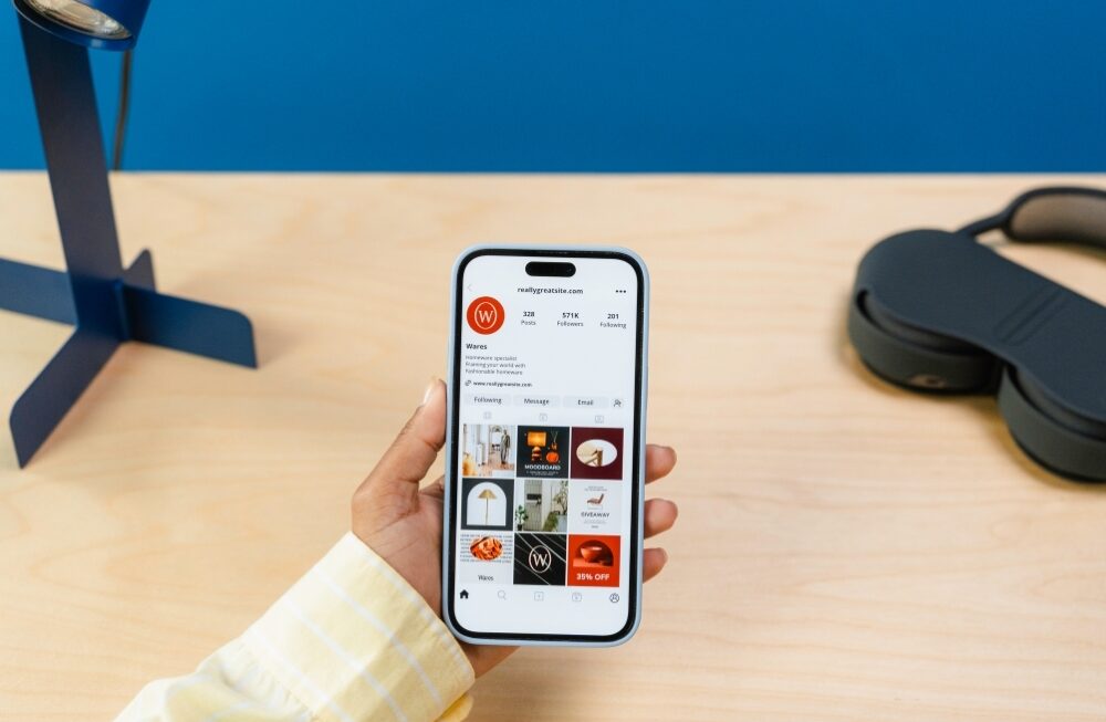 Hand holding phone with Instagram business profile on screen, showing brand content by social media marketing agency in gurgaon